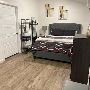 A bedroom with a bed, a nightstand, a wall-mounted shelf, and a door. - Nice studio apartment 13 minutes from downtown Dallas. (Grand Prairie)