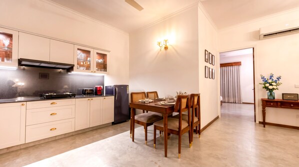 Una cocina moderna con armarios blancos, una mesa de comedor con sillas y vistas al área de estar.