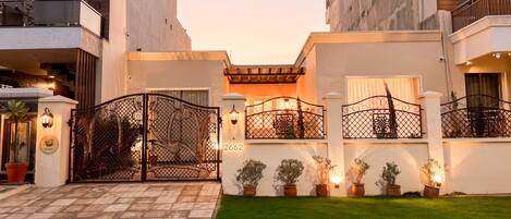 A gated entrance with a wrought iron gate, potted plants, and a well-maintained lawn.