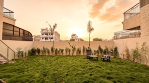 A grassy courtyard with a seating area and a view of buildings in the background.
