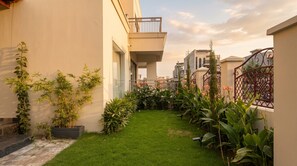 Un patio residencial con césped, plantas en macetas y una reja de metal.