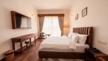 A hotel room with a bed, bedside table, lamp, chair, and a TV mounted on the wall.