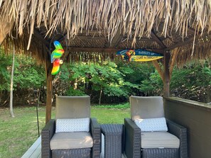 Two wicker chairs with cushions under a thatched roof structure. - Traverse City Tiki House (Traverse City)