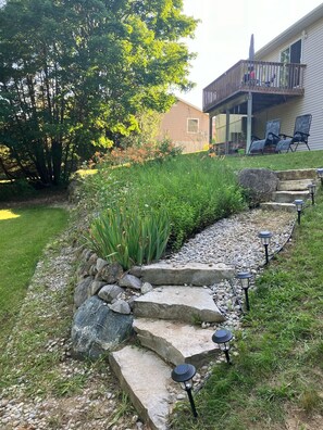 A landscaped garden with a stone pathway, solar lights, and a tree. - Traverse City Tiki House (Traverse City)