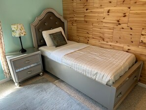 A bedroom with a bed, a nightstand, a lamp, and a wooden headboard. - Traverse City Tiki House (Traverse City)