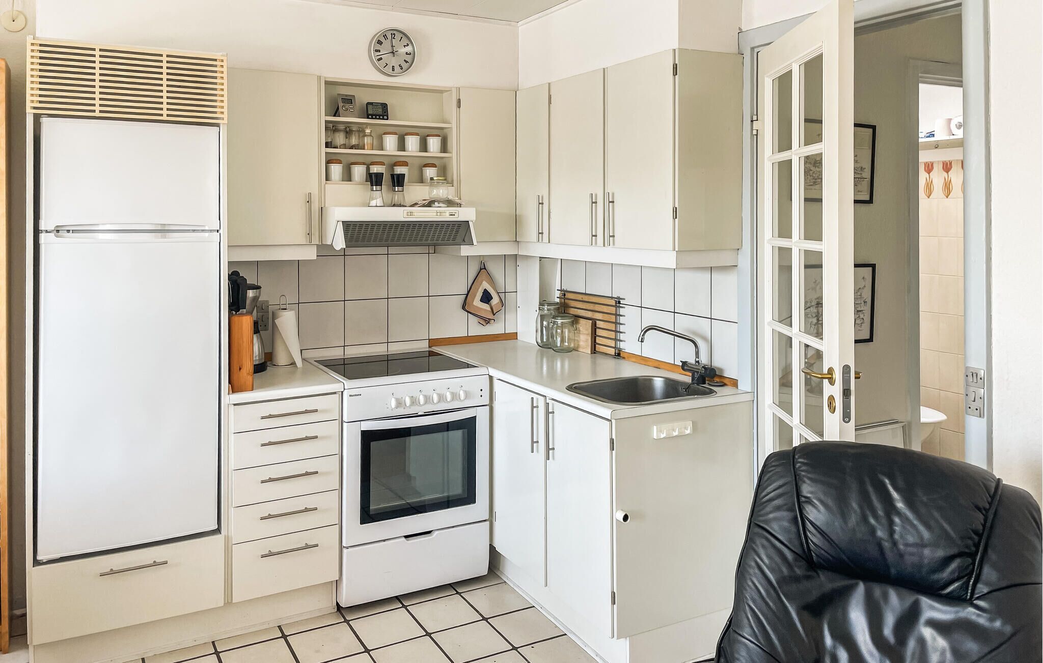 Une cuisine de taille réduite avec des meubles blancs, une cuisinière et un évier.