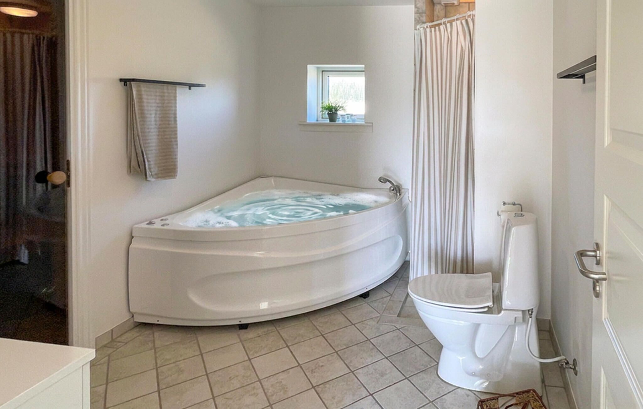 A bathroom with a freestanding bathtub, a toilet, and a window.