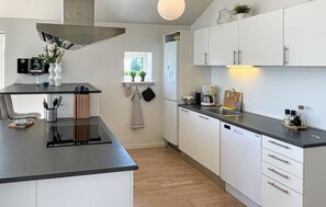 Une cuisine moderne avec des armoires blanches, un plan de travail noir et un lave-vaisselle encastré.