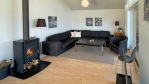 A modern living room with a black sofa, a coffee table, a fireplace, and two wall-mounted lamps. - Gorgeous home in Rudkøbing with sauna (Rudkøbing)
