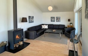 Ein modernes Wohnzimmer mit einer schwarzen Couch, einem Couchtisch, einem Kamin und zwei Wandlampen.