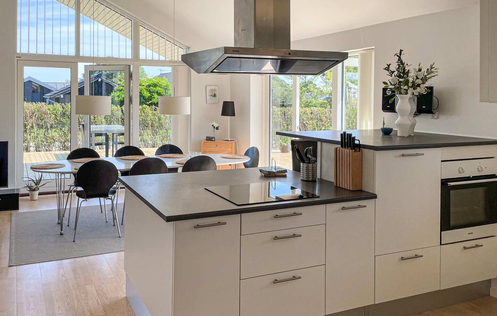 A modern kitchen with a large island, integrated oven, and a dining area with a view of the outdoors.