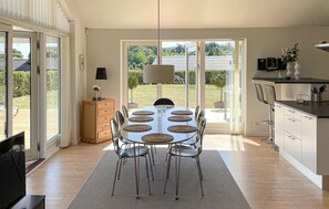 Eine moderne Küche mit Essbereich, großen Fenstern und Blick ins Freie.