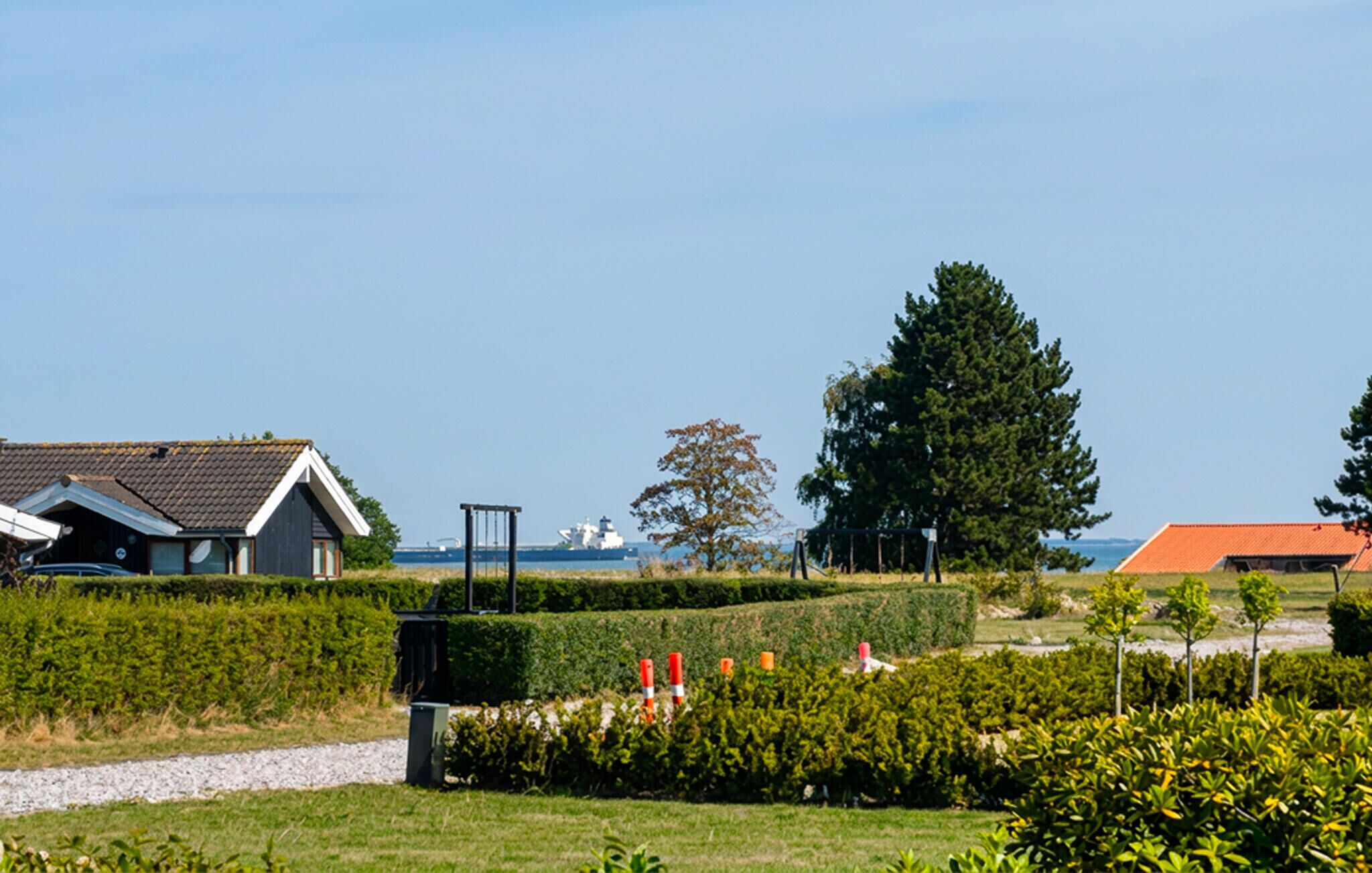 A residential area with houses, a large tree, and a body of water in the background.