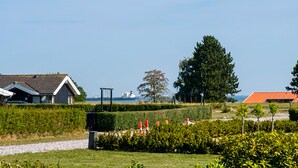 A residential area with houses, a large tree, and a body of water in the background. - Gorgeous home in Rudkøbing with sauna (Rudkøbing)