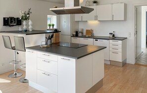 A modern kitchen with white cabinetry, a central island, and bar stools. - Gorgeous home in Rudkøbing with sauna (Rudkøbing)