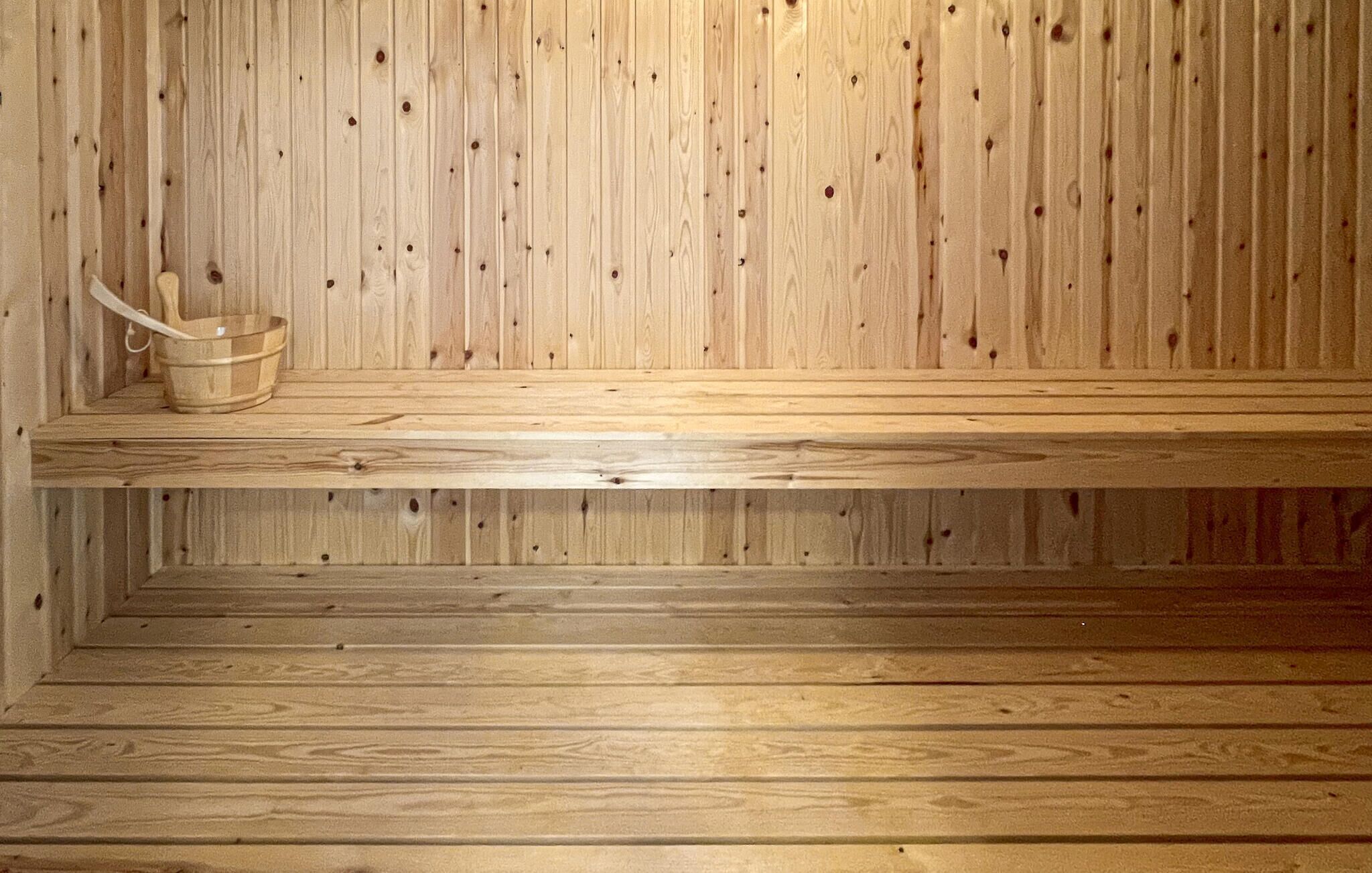 Een houten sauna met een bank en een emmer.