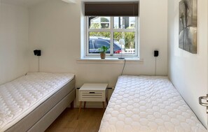 Une petite chambre propre, avec deux lits simples, une fenêtre donnant sur la rue et une petite table agrémentée d’une plante.