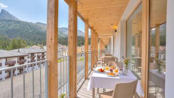 A balcony with a table set for breakfast, overlooking a mountainous landscape.