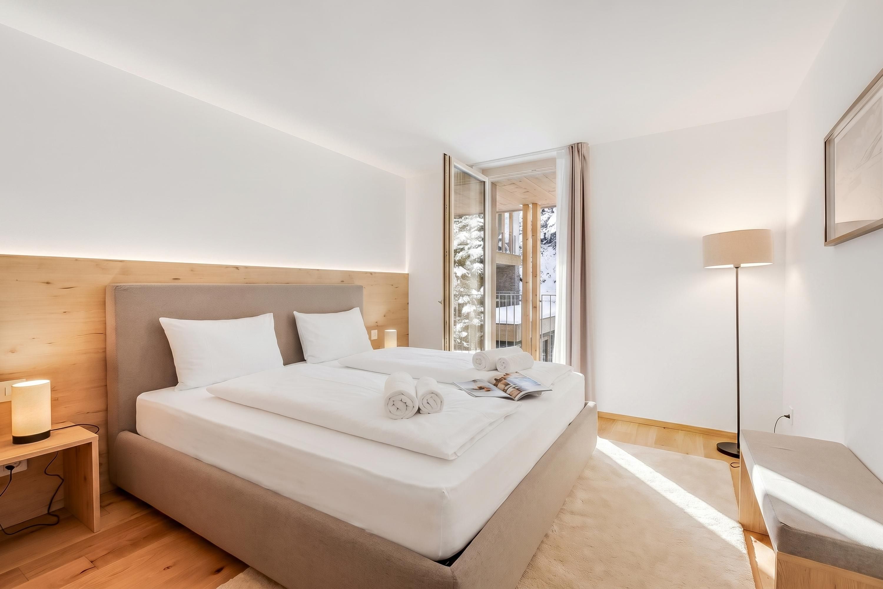Una camera da letto moderna con un letto grande, un comodino, una lampada da terra e uno specchio.