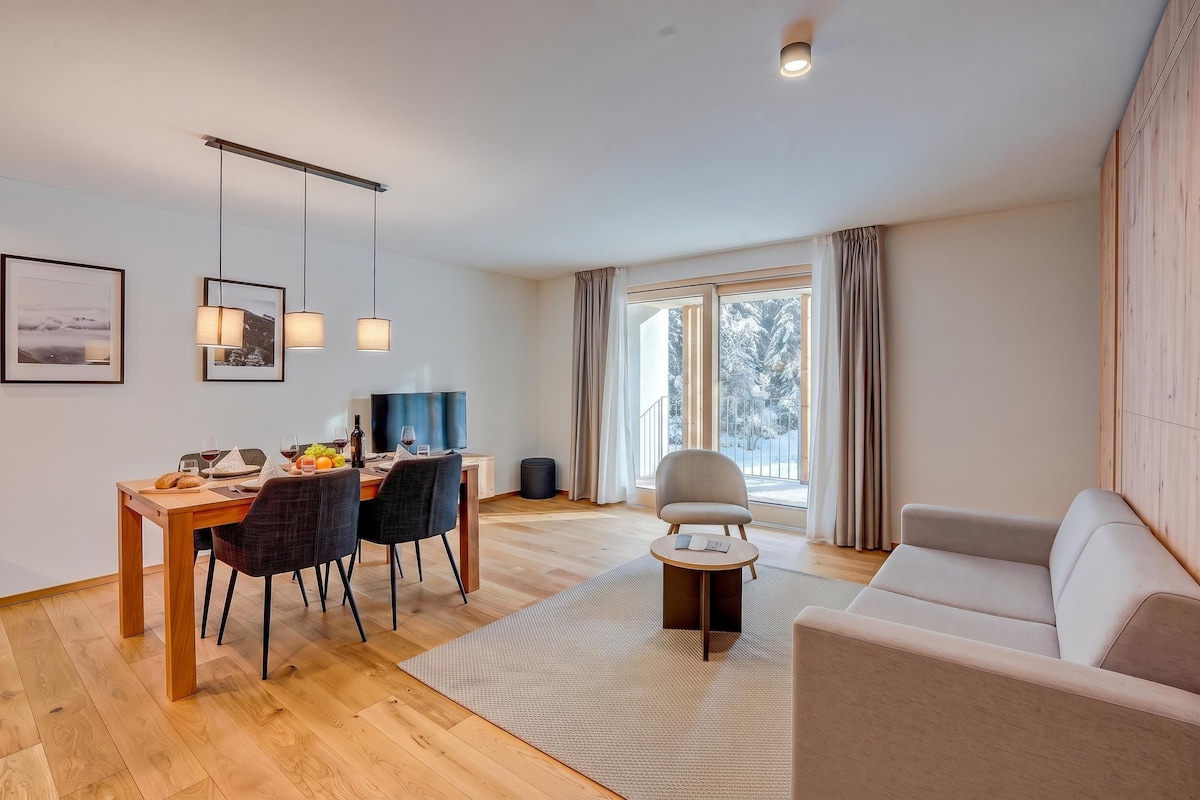 A modern living room with a dining area, a sofa, a coffee table, and a TV.