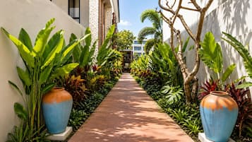 A pathway flanked by large planters and a building with a textured wall.