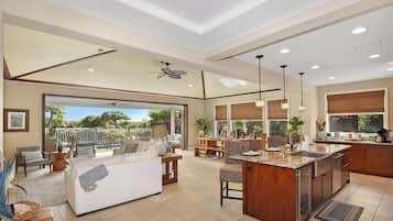 A spacious living area with a large sofa, dining table, and a kitchen with a central island.