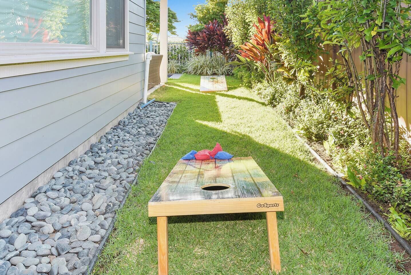 A backyard with a wooden table, a small garden, and a house.