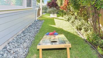 A backyard with a wooden table, a small garden, and a house.