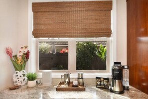 A kitchen with a window, a coffee maker, a kettle, and a tray with a teapot. - Island Time-Luxury Golf Front Home with Pool/Spa (Kailua-Kona)