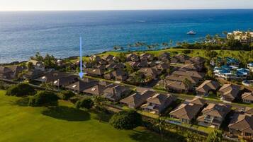 A coastal residential area with houses, a golf course, and a view of the ocean.