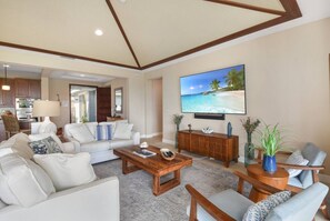 A spacious living room with a large flat-screen TV, a wooden coffee table, and a comfortable seating area. - Island Time-Luxury Golf Front Home with Pool/Spa (Kailua-Kona)