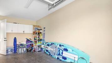 A room with a surfboard, storage cabinets, and a ceiling fan.