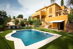 A residential property with a swimming pool, a covered patio, and a staircase leading to the entrance.