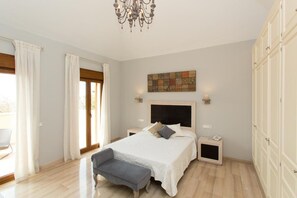 Un dormitorio con cama, mesitas de noche, un banco, un candelabro, un cuadro y un armario.