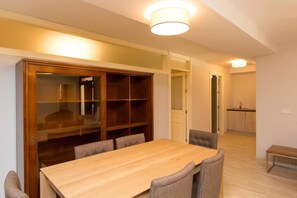 A dining area with a wooden table and chairs, a built-in bookshelf, and a kitchen in the background. - Villas Lomas de Marbella (Marbella)
