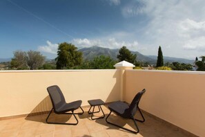 A terrace with two chairs and a small table, overlooking a mountainous landscape.