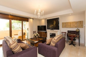 A living room with a sofa, coffee table, TV, fireplace, and artwork.
