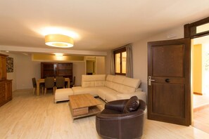 A living room with a sectional sofa, a coffee table, a leather armchair, and a dining area with a table and chairs. - Villas Lomas de Marbella (Marbella)