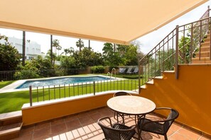 Un espacio al aire libre techado con piscina, una mesa y sillas.