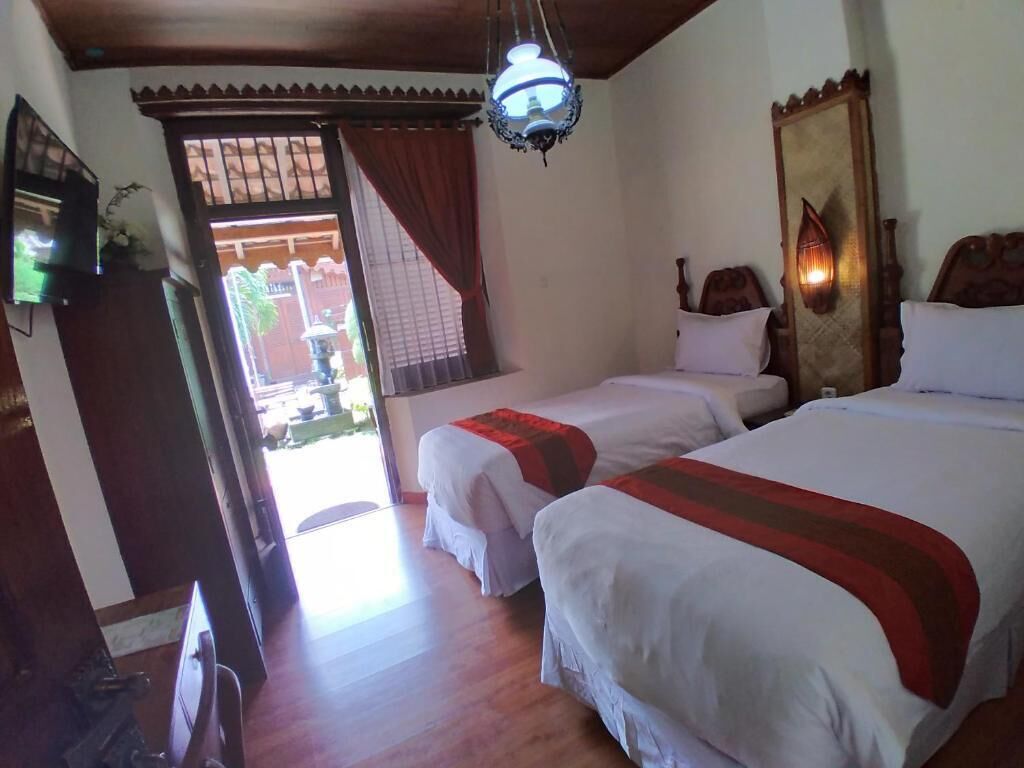 A hotel room with two beds, a wooden ceiling, a large mirror, and a view of the outside.