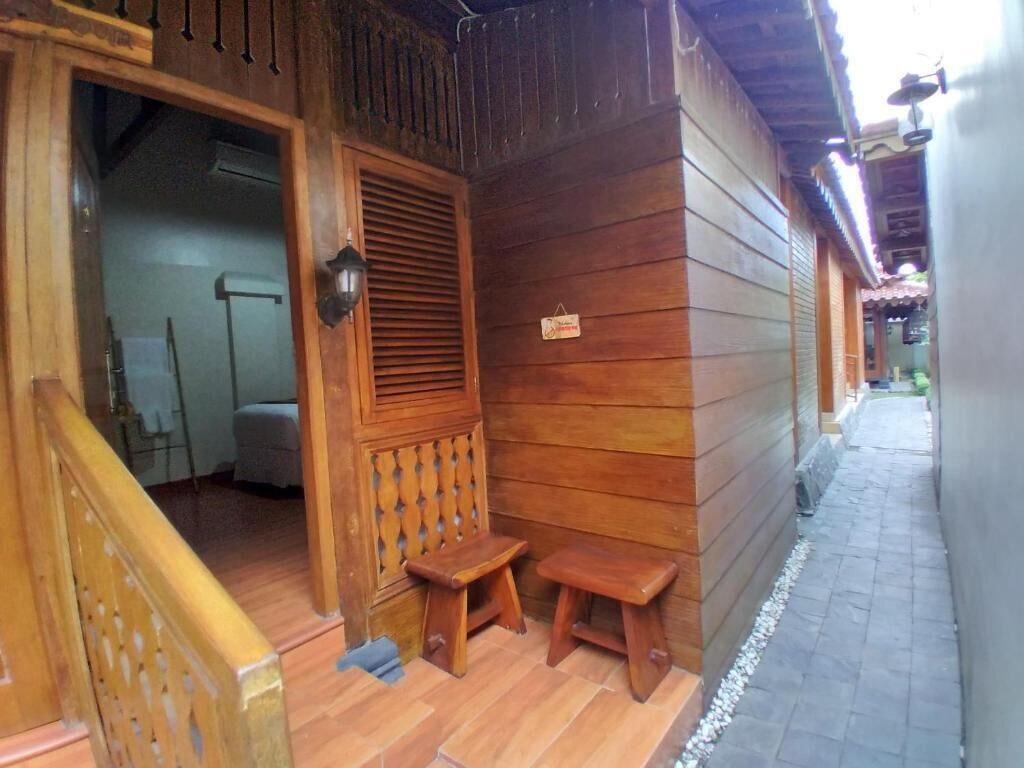 Fachada de madera con un porche, un banco de madera pequeño y un cartel en la pared.