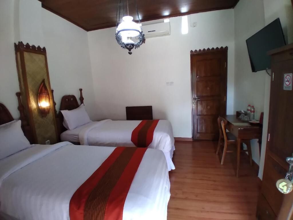 A hotel room with two beds, a desk, a television, and a wardrobe.