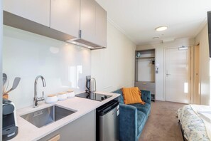 A compact kitchenette with a sink, stove, and a coffee maker. - Studio for 2 in Central Te Aro Stay! (Wellington)