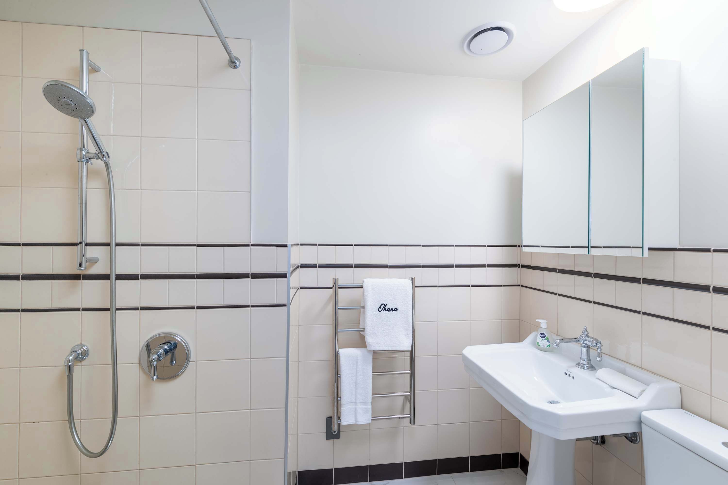 A modern bathroom with a shower, sink, and toilet.