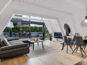 Een ruime loft met hoge plafonds, een eethoek en een zithoek met een bank en salontafel.