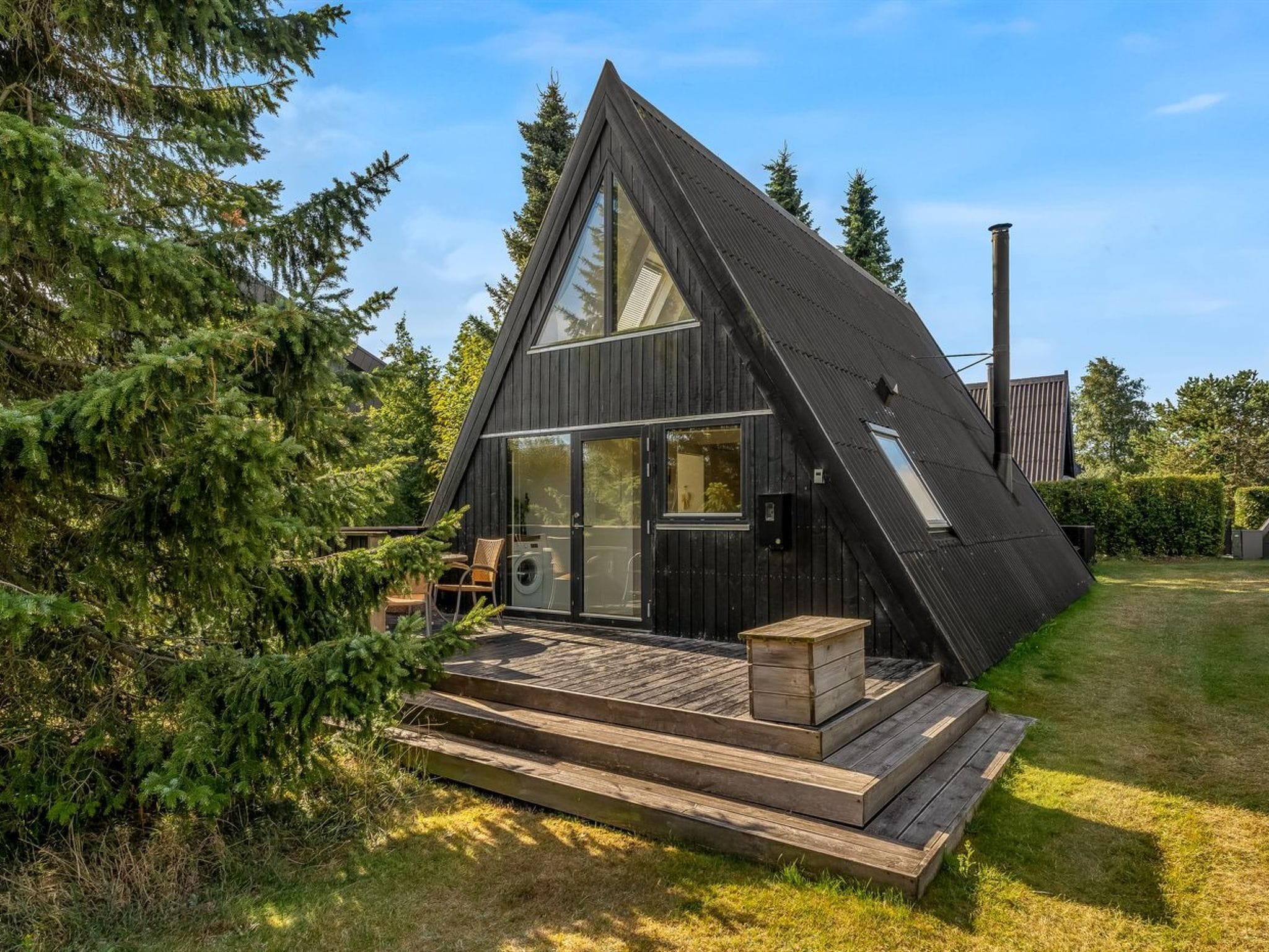 A modern house with a sloped roof, large windows, and a wooden deck.