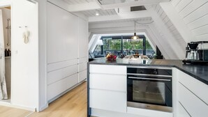 Una cocina moderna con una isla central, horno empotrado y vistas a través de un tragaluz.