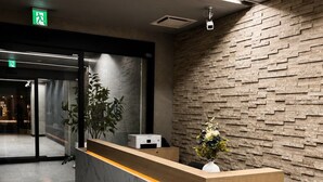 Una recepción con un panel de mármol, una planta en maceta y una pared con textura.