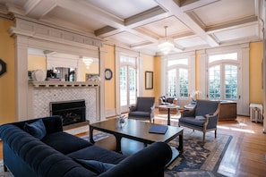 A spacious living room with a fireplace, comfortable seating, and large windows.