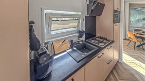 A compact kitchen with a built-in stove, a sink, and a window with blinds. - 2 bedroom lovely home in Oude Pekela (Oude Pekela)